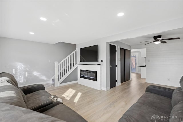 living room featuring light wood-type flooring, recessed lighting, ceiling fan, and a glass covered fireplace