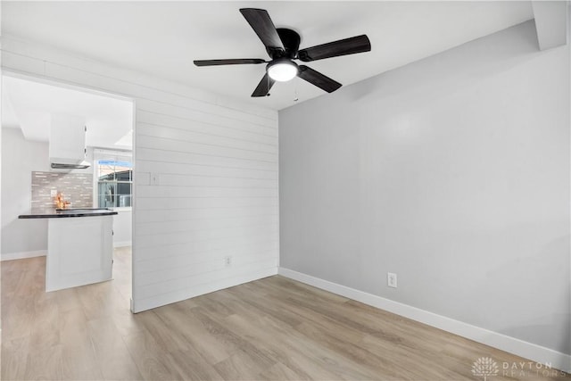 spare room with light wood-style floors, baseboards, and a ceiling fan