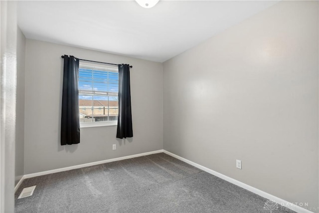 unfurnished room featuring visible vents, baseboards, and dark colored carpet