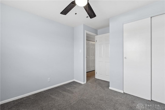 unfurnished bedroom featuring baseboards, dark carpet, ceiling fan, and a closet