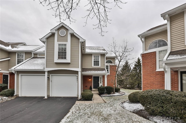 traditional home featuring aphalt driveway, brick siding, and a garage