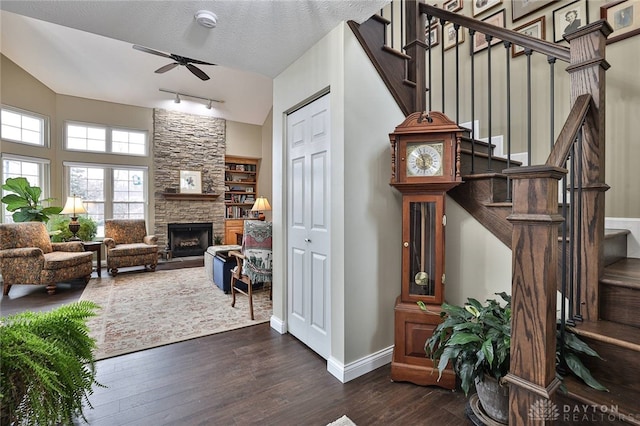 interior space featuring a fireplace, dark wood-type flooring, ceiling fan, a textured ceiling, and stairs