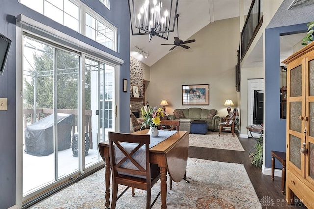 dining area featuring visible vents, dark wood finished floors, baseboards, a stone fireplace, and high vaulted ceiling