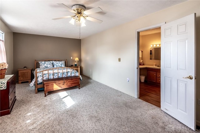 carpeted bedroom featuring a sink, ensuite bath, and ceiling fan