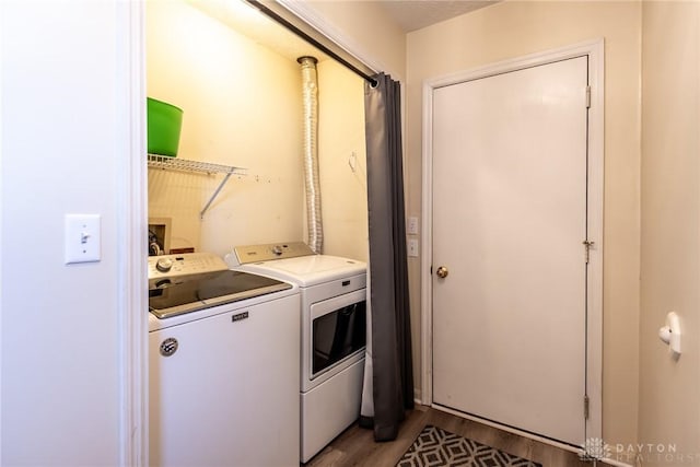 clothes washing area with washer and dryer, laundry area, and light wood-style flooring