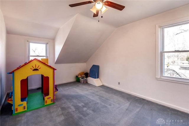 recreation room with vaulted ceiling, carpet flooring, a ceiling fan, and baseboards