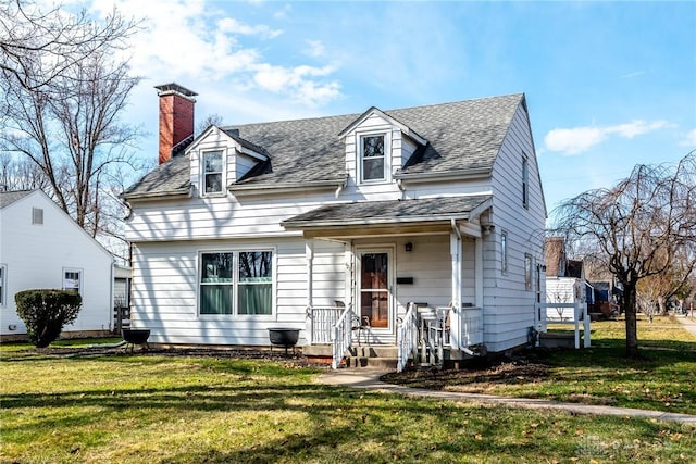 new england style home featuring roof with shingles, a chimney, and a front yard