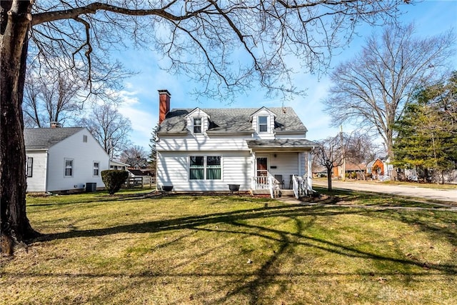 new england style home featuring roof with shingles, a front lawn, a chimney, and cooling unit