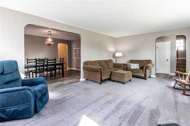 carpeted living room featuring stairway, baseboards, and arched walkways