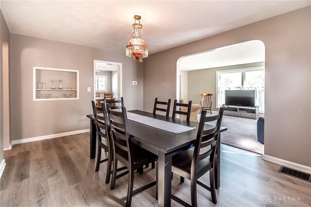 dining room featuring visible vents, arched walkways, a wealth of natural light, and wood finished floors