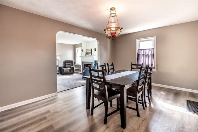 dining area featuring baseboards, a fireplace, visible vents, and wood finished floors