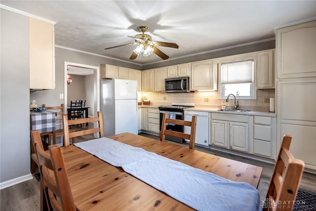 kitchen featuring crown molding, stainless steel appliances, a sink, and decorative backsplash