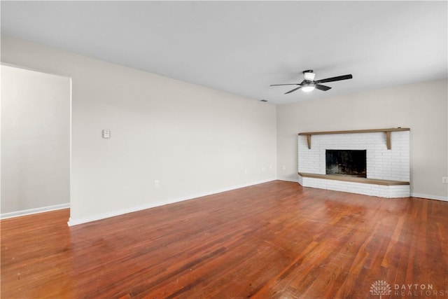 unfurnished living room featuring baseboards, a fireplace, a ceiling fan, and wood finished floors