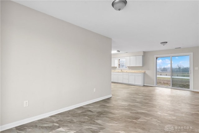 unfurnished living room featuring baseboards and a sink