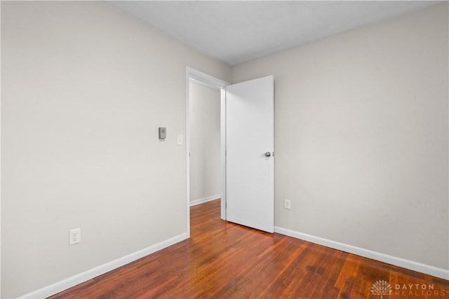 spare room with baseboards and wood finished floors