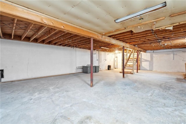 unfinished basement featuring water heater and stairway