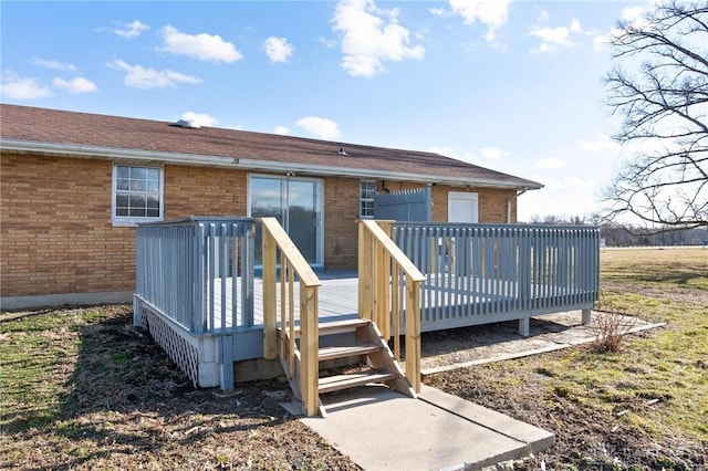 back of property with brick siding, a wooden deck, and roof with shingles