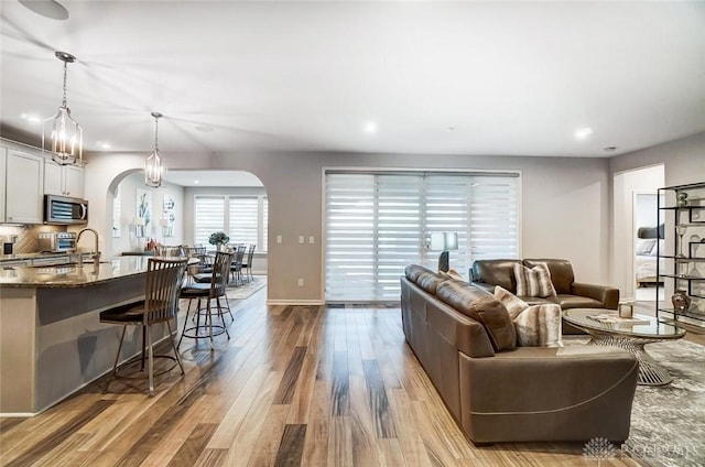 living room with arched walkways, recessed lighting, baseboards, and wood finished floors