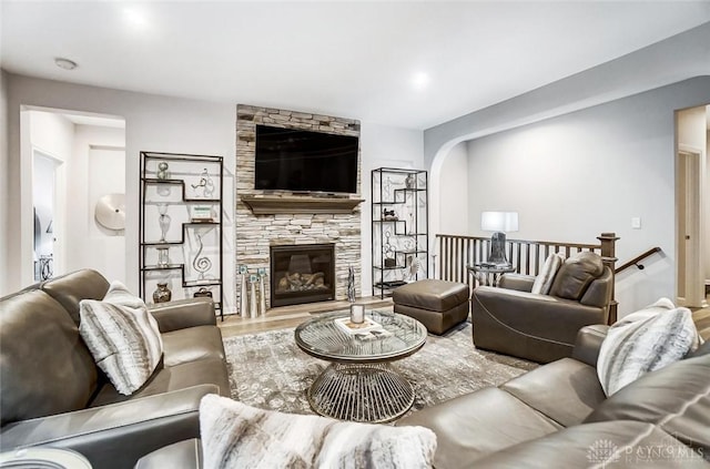 living area with arched walkways, a fireplace, and wood finished floors