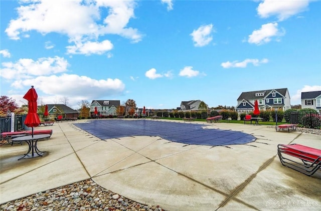 view of pool with a patio, fence, and a residential view