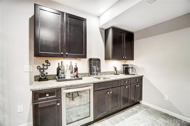 bar featuring beverage cooler, bar, a sink, and baseboards