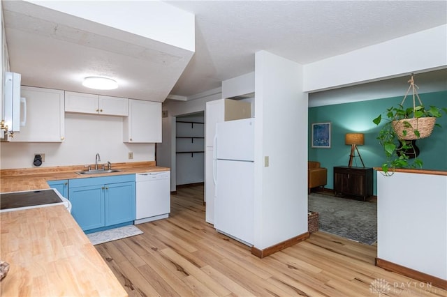 kitchen with butcher block countertops, light wood-type flooring, white appliances, and a sink