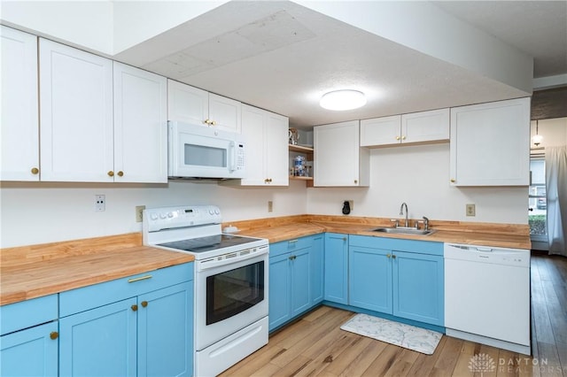 kitchen featuring blue cabinets, white appliances, butcher block countertops, and a sink