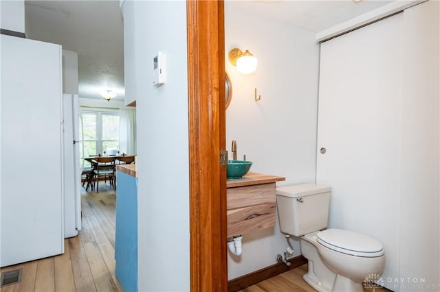 bathroom featuring visible vents, vanity, toilet, and wood finished floors