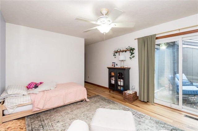 bedroom with a ceiling fan, access to outside, visible vents, and wood finished floors