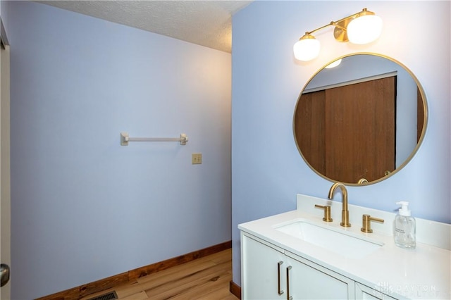 bathroom with vanity, baseboards, a textured ceiling, and wood finished floors