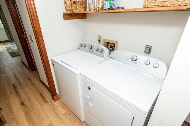 clothes washing area featuring light wood-style floors, laundry area, and washing machine and clothes dryer