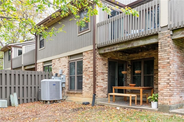 back of house featuring fence, cooling unit, and brick siding