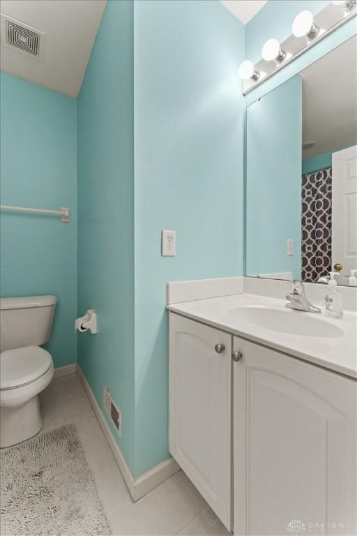 bathroom with visible vents, baseboards, toilet, tile patterned flooring, and vanity