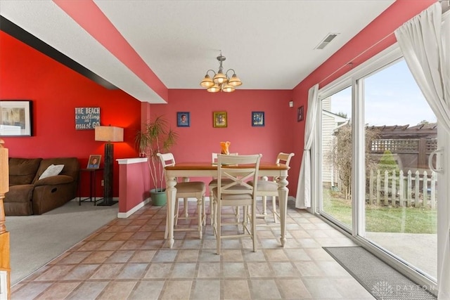 dining space featuring light colored carpet, visible vents, an inviting chandelier, an accent wall, and baseboards