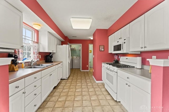 kitchen with light countertops, white cabinetry, a sink, white appliances, and baseboards