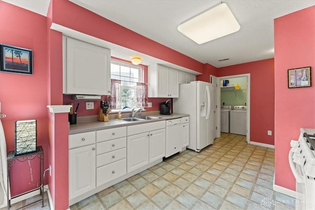 kitchen with white appliances, a sink, white cabinets, light countertops, and independent washer and dryer