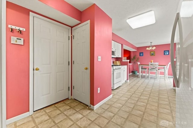 kitchen with white appliances, baseboards, and white cabinets