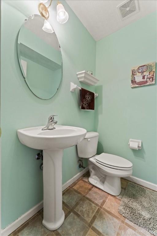 bathroom with baseboards, visible vents, and toilet