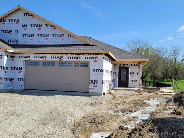 view of front of house with a shingled roof and dirt driveway