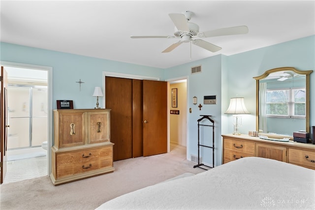 bedroom featuring a closet, light colored carpet, visible vents, ensuite bathroom, and a ceiling fan