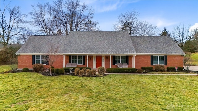 view of front of property featuring covered porch, a front lawn, and brick siding