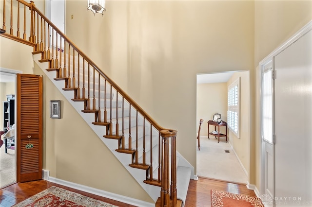 entryway featuring wood-type flooring, a towering ceiling, and baseboards