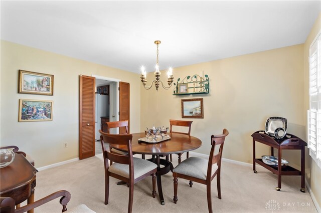 dining space featuring light carpet, baseboards, and a chandelier