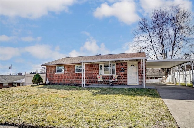 view of front of property featuring concrete driveway, fence, a front lawn, a carport, and brick siding