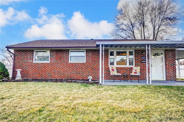 view of front of home with roof with shingles, brick siding, and a front lawn