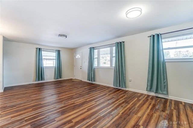 empty room with plenty of natural light, wood finished floors, and baseboards