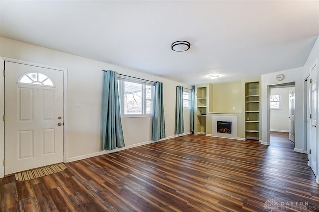 unfurnished living room featuring a fireplace, baseboards, and wood finished floors