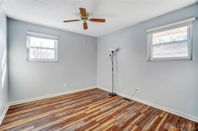 empty room with visible vents, ceiling fan, baseboards, and wood finished floors