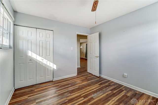 unfurnished bedroom featuring a ceiling fan, a closet, baseboards, and wood finished floors