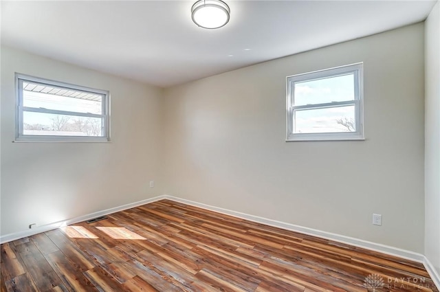 unfurnished room with wood finished floors, visible vents, and baseboards